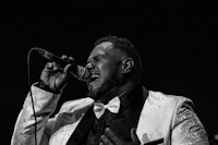 a man in a tuxedo singing into a microphone