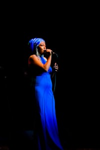 a woman in a blue dress singing into a microphone