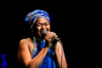 a woman in a blue dress singing into a microphone