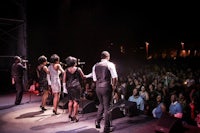 a group of people singing on stage in front of an audience